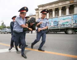 Полицейлер наразылық акциясына қатысушыны көлікке күштеп салуға әкеле жатыр. Алматы, 10 маусым 2019 жыл.